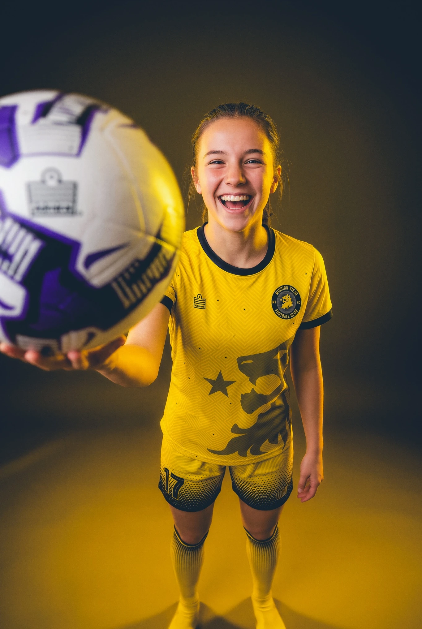 Mission Viejo FC goalkeeper in a gold and purple kit holding a ball